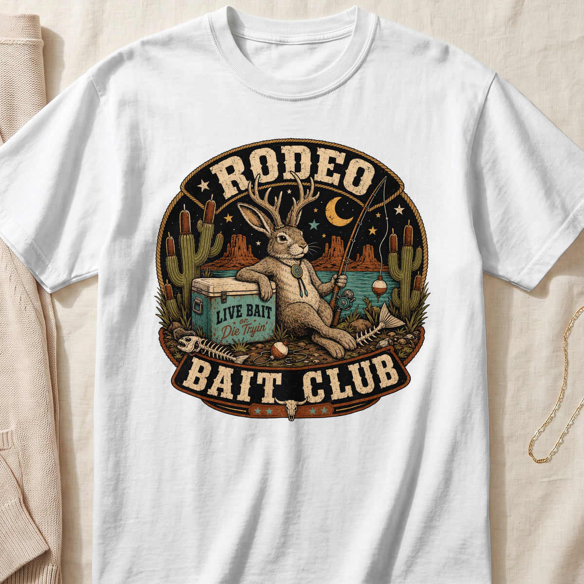 White t-shirt with "RODEO BAIT CLUB" design featuring a rabbit with antlers fishing.