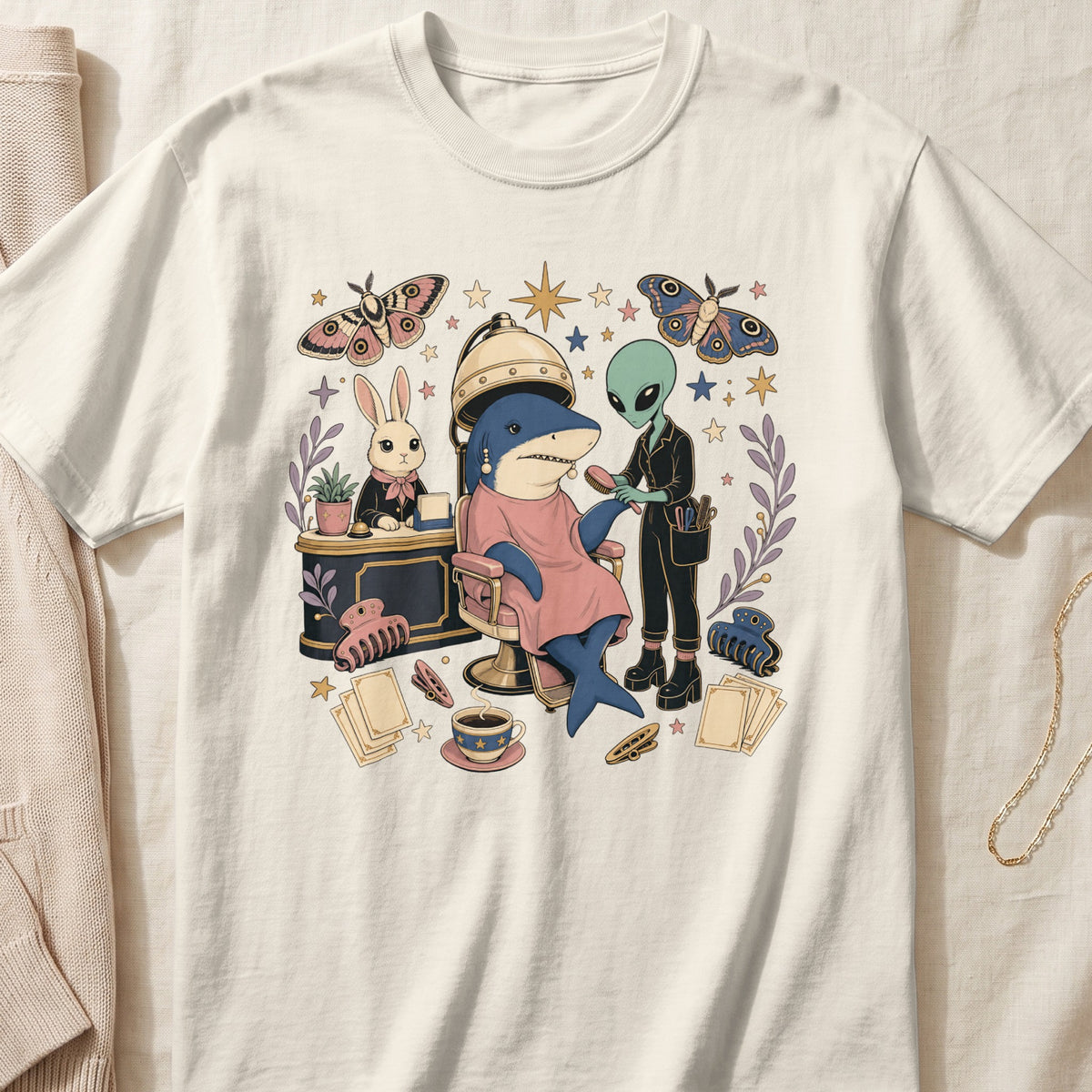 A cream t-shirt featuring a surreal cartoon illustration of an alien styling a shark's hair.