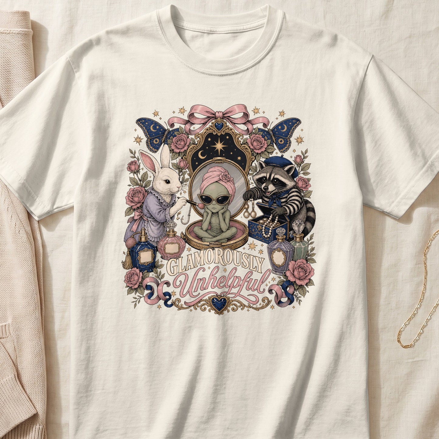 White t-shirt graphic with alien, rabbit, raccoon, perfumes, and "Glamorously Unhelpful" text.