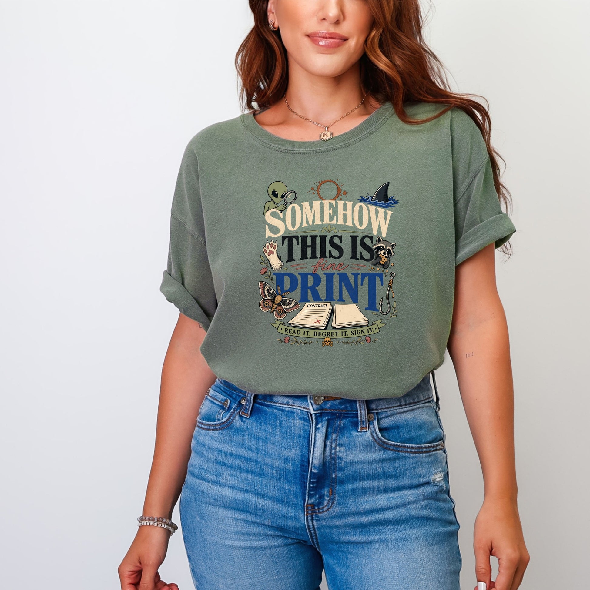 A woman wearing an olive green t-shirt with a vintage-style graphic and blue jeans.
