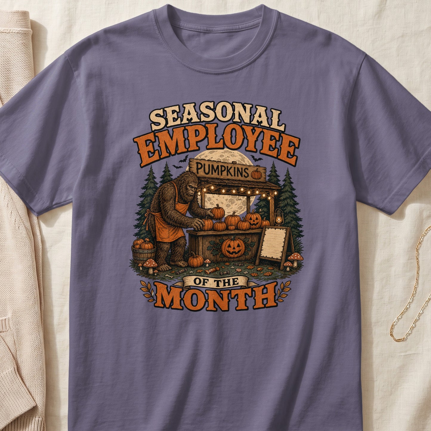 Bigfoot wearing an apron sells pumpkins at a stand with text "Seasonal Employee Of The Month".
