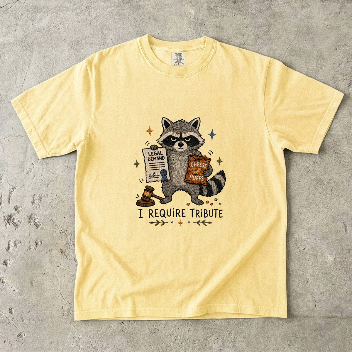 Yellow t-shirt with raccoon holding "Legal Demand" and "Cheese Puffs", saying "I Require Tribute".