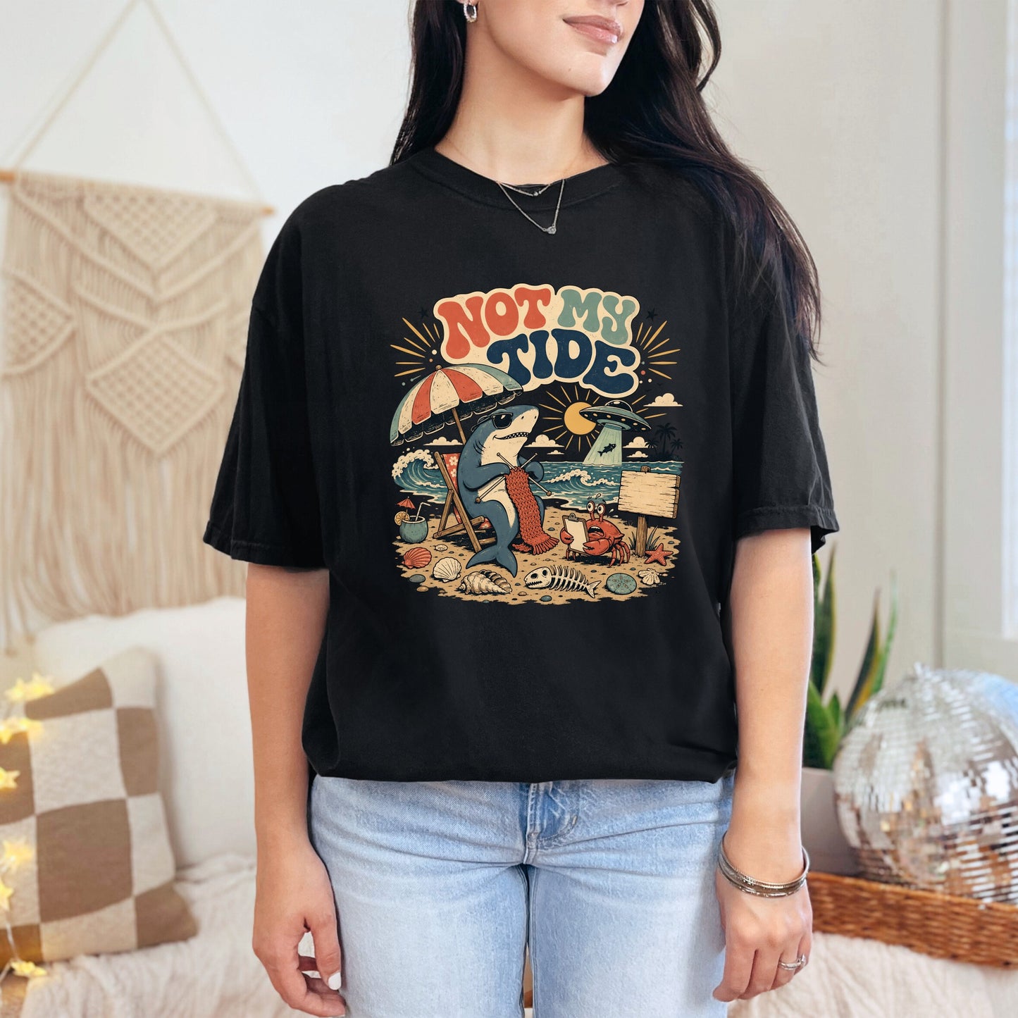 Black t-shirt with "Not My Tide" text and a shark knitting on a beach.