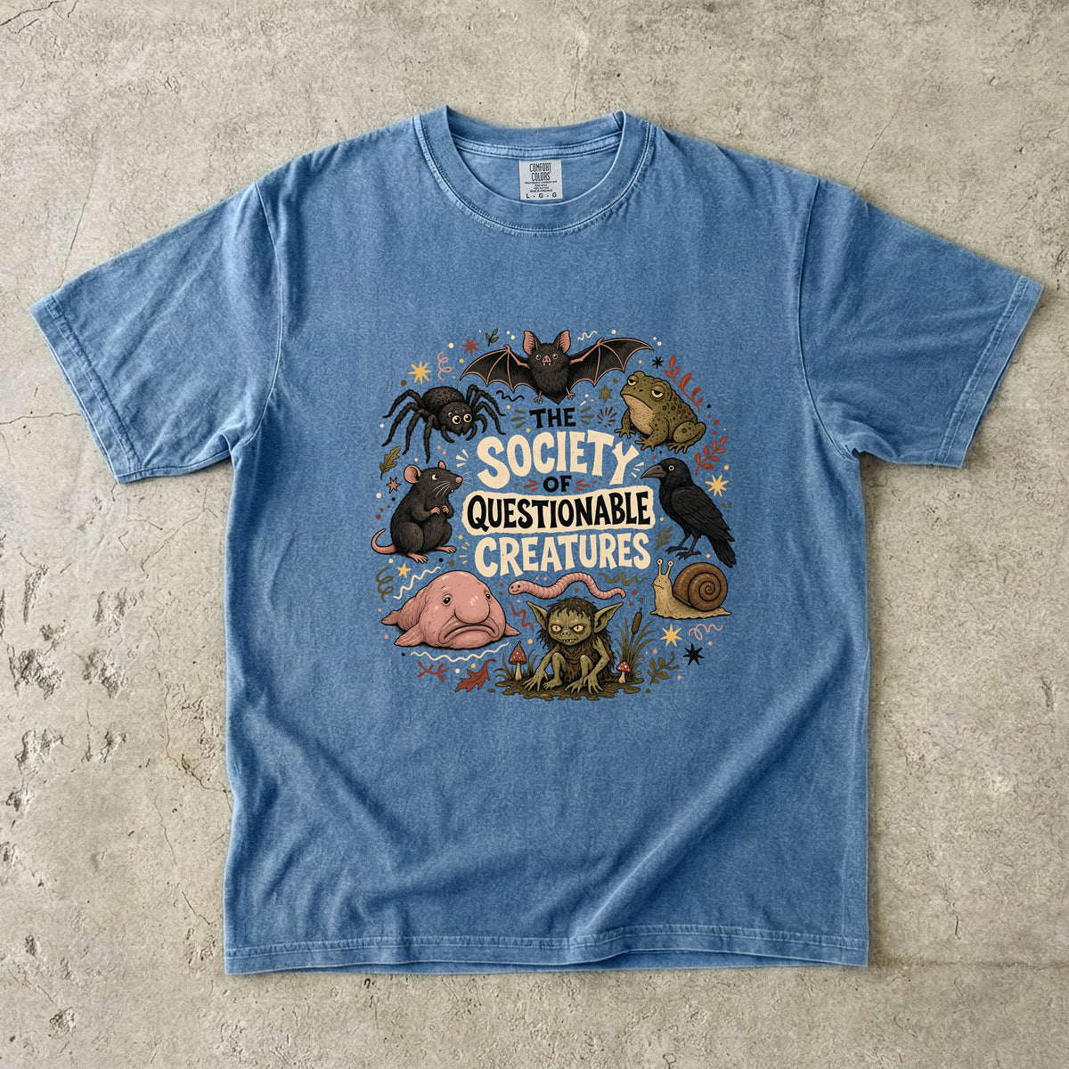 Blue t-shirt with a circular graphic of "The Society of Questionable Creatures" featuring various animals.