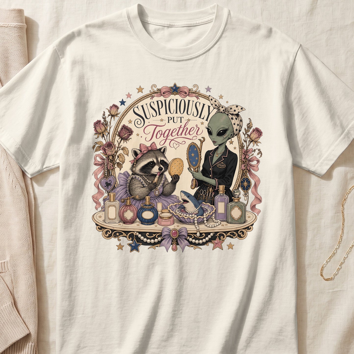 Off-white t-shirt featuring a vintage illustration of a raccoon and alien surrounded by makeup and text reading Suspiciously Put Together.