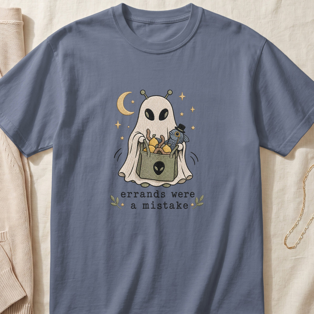 A slate blue t-shirt embroidered with a ghost holding a grocery bag and the text errands were a mistake.