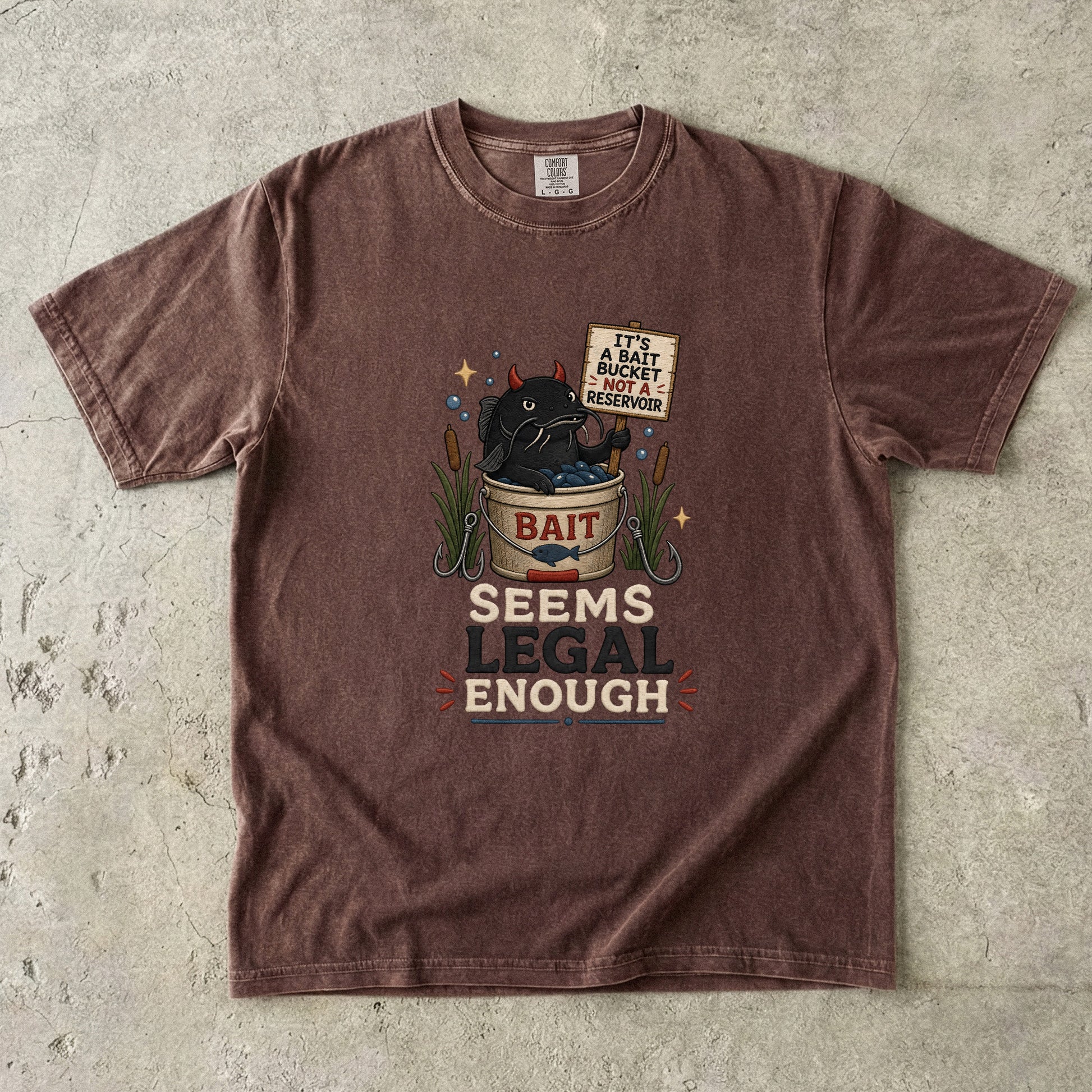 Brown t-shirt graphic of a devil catfish in a bait bucket with text.