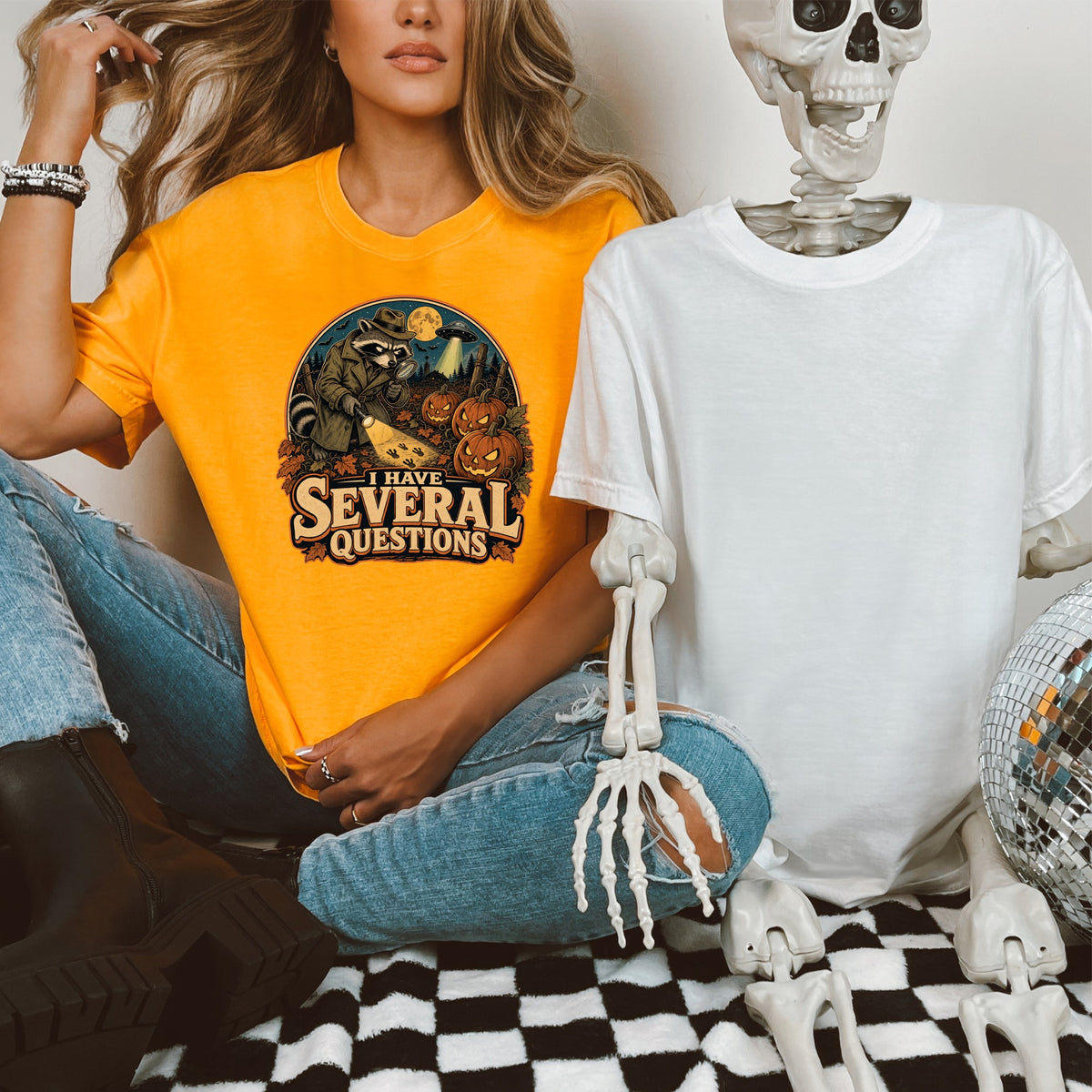 Orange t-shirt graphic features raccoon detective with text "I HAVE SEVERAL QUESTIONS."