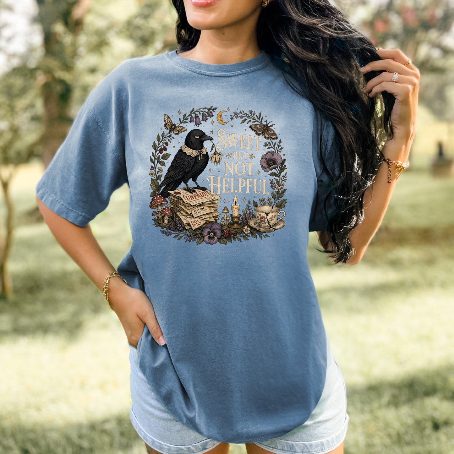 T-shirt graphic with a crow on unpaid bills, text "SWEET BUT NOT HELPFUL".