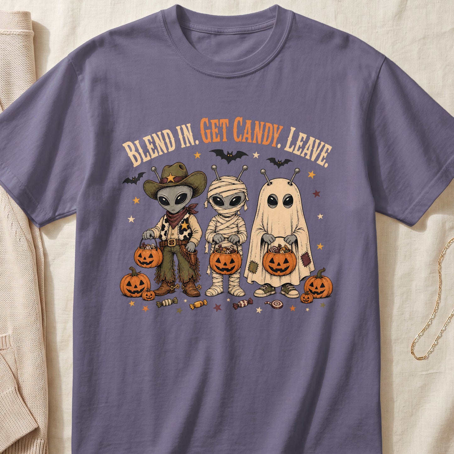 Three aliens dressed as a cowboy, mummy, and ghost hold candy buckets.