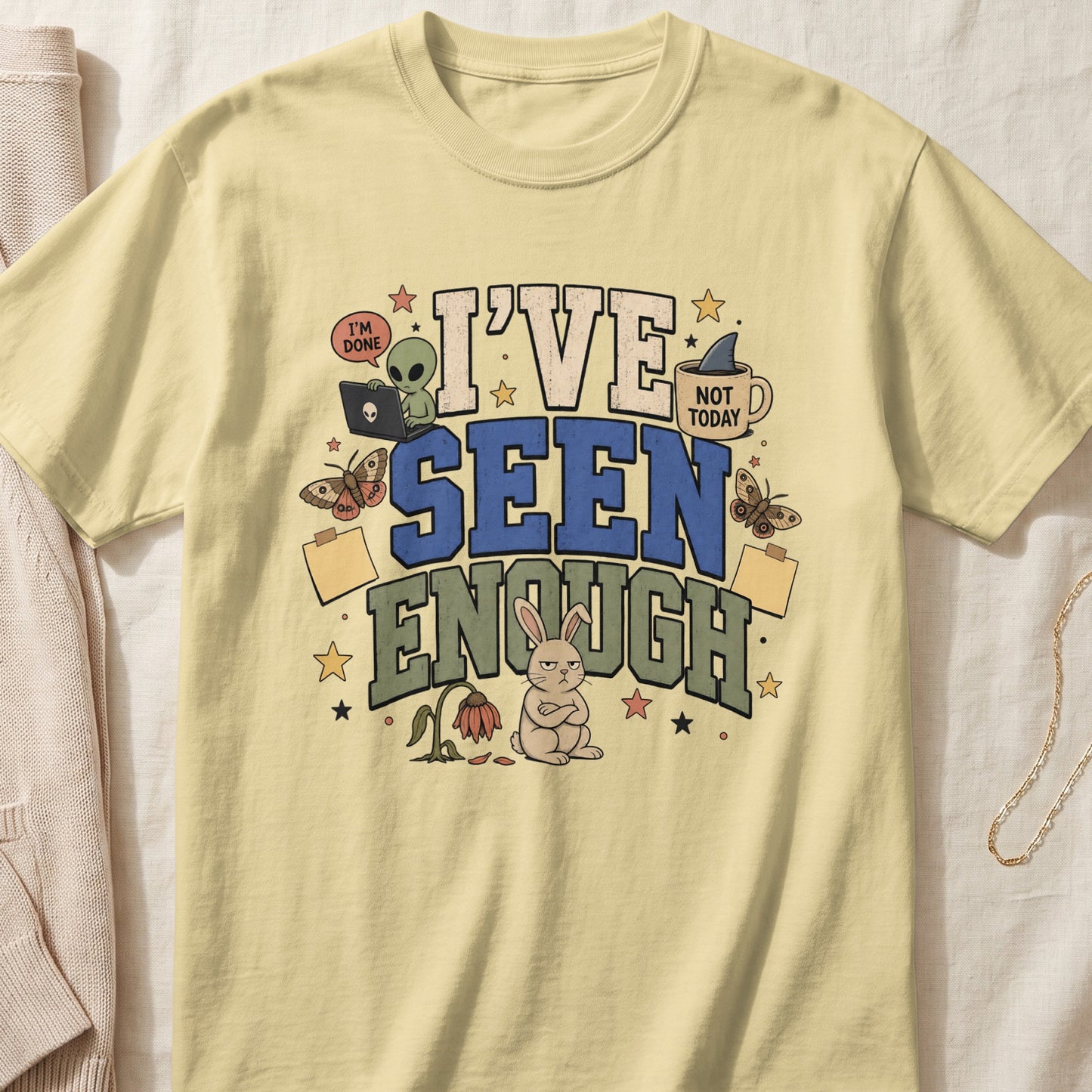 Light yellow t-shirt with "I've Seen Enough" text and cartoon alien, bunny, and moths.