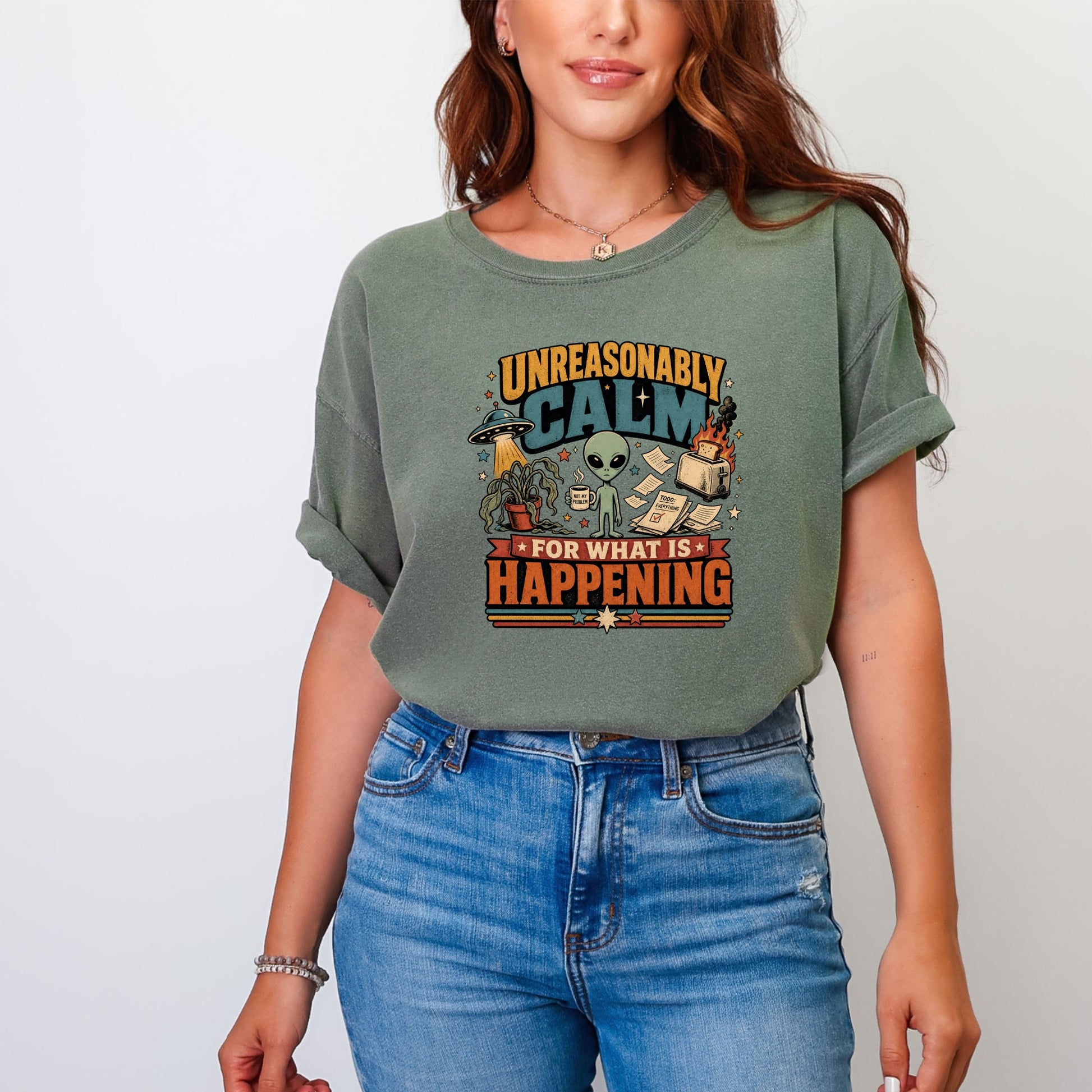 Green t-shirt with graphic "Unreasonably Calm For What Is Happening" and an alien drinking coffee.