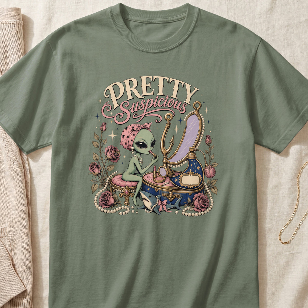 Alien applying makeup with text "Pretty Suspicious," roses, pearls, and shark.