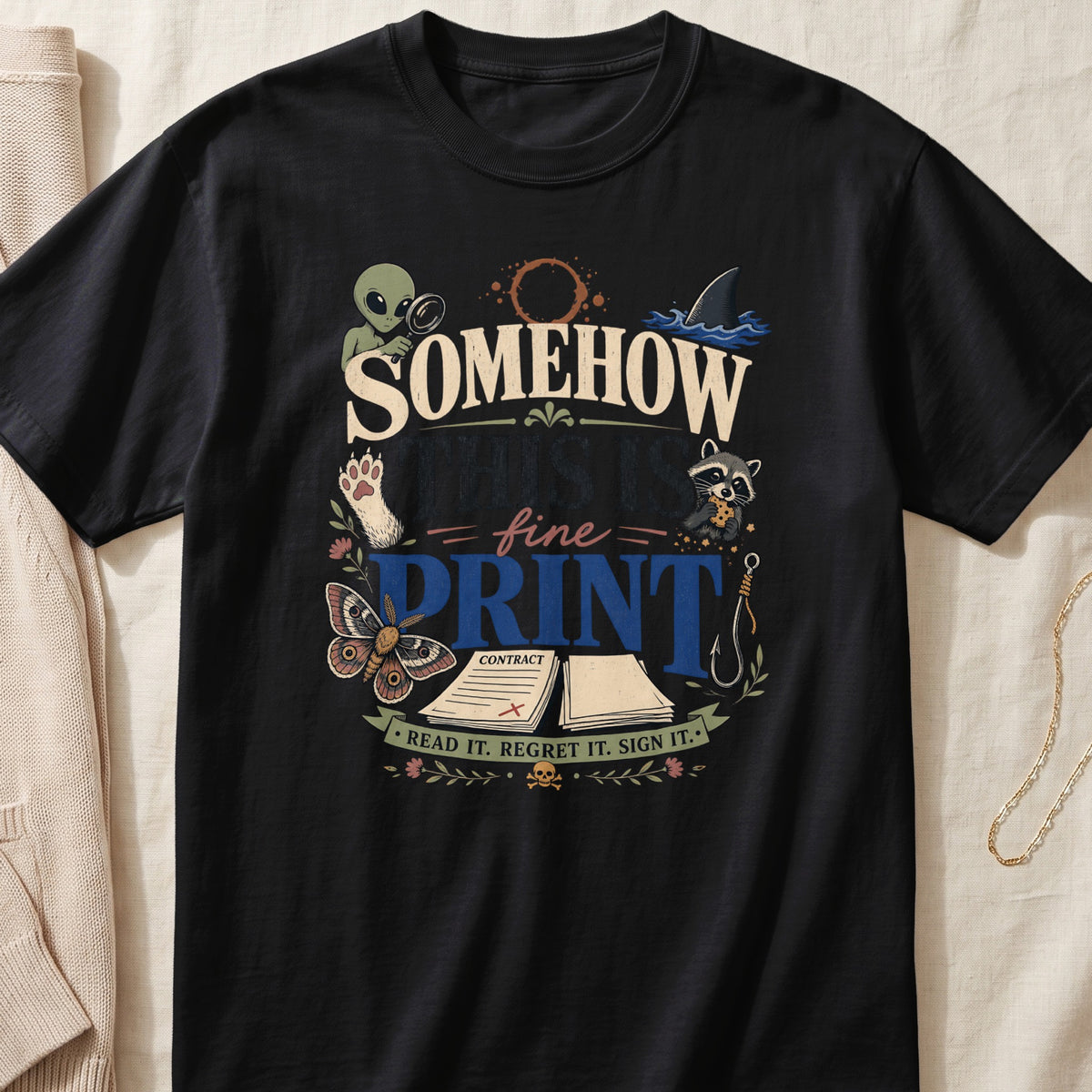 A black crew-neck t-shirt featuring a colorful graphic and the text "SOMEHOW THIS IS FINE PRINT READ IT. REGRET IT. SIGN IT."
