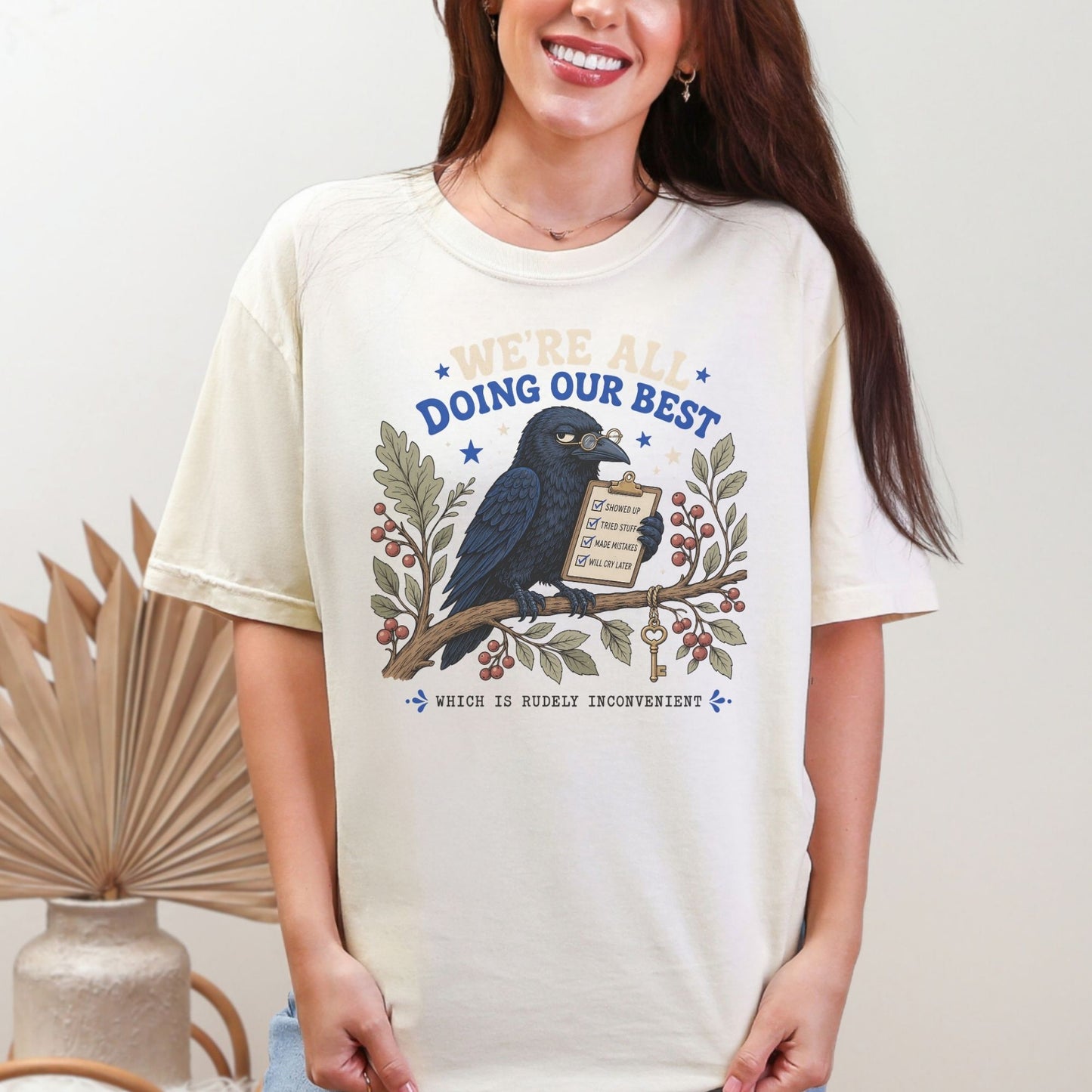 Cream t-shirt with crow on branch holding clipboard listing tasks.
