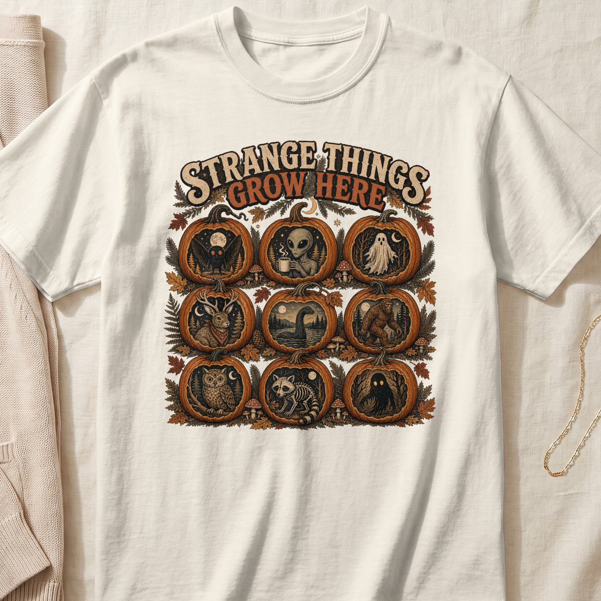 "Strange Things Grow Here" text over pumpkins featuring cryptids and Halloween figures.