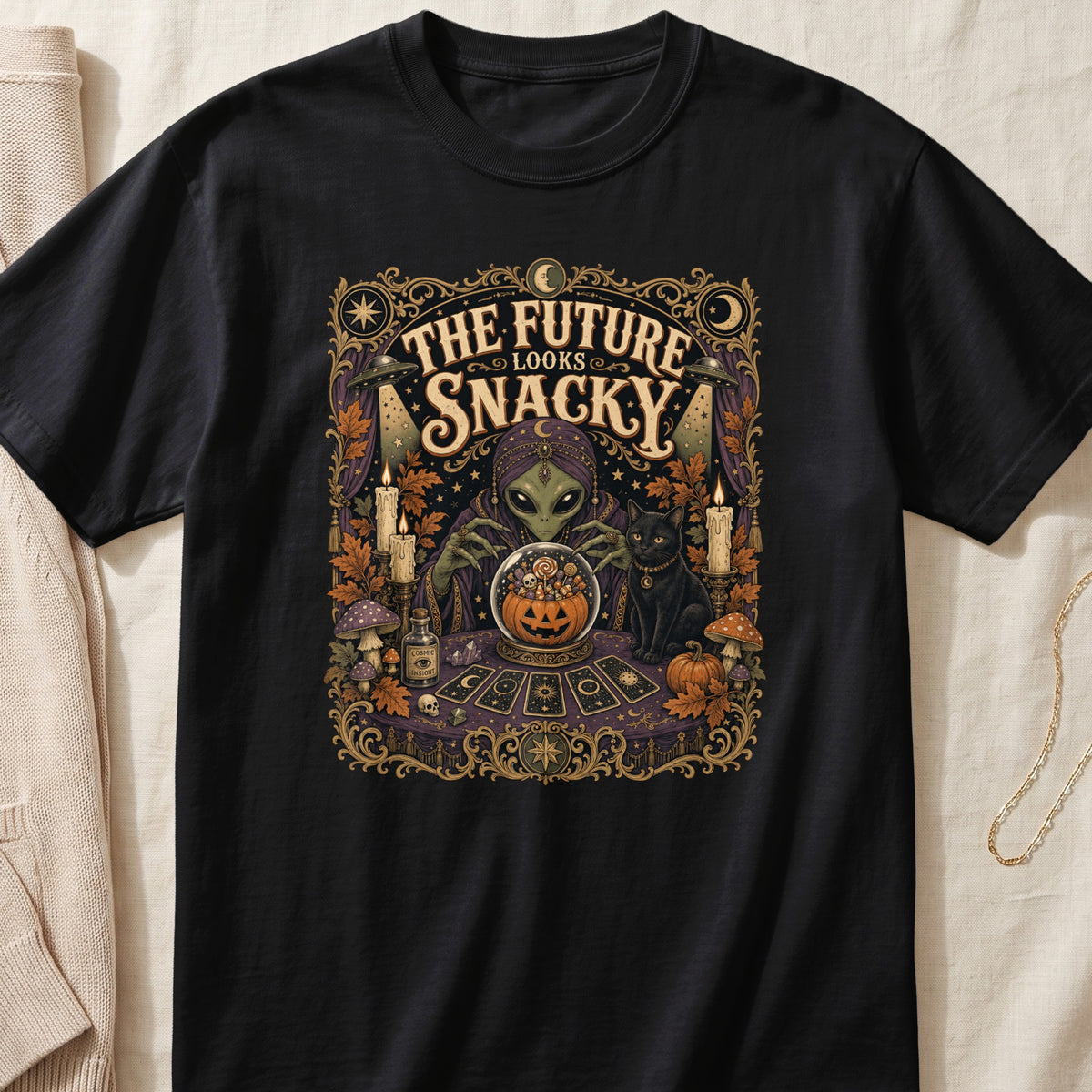 Alien fortune teller with black cat and crystal ball reads "The Future Looks Snacky".