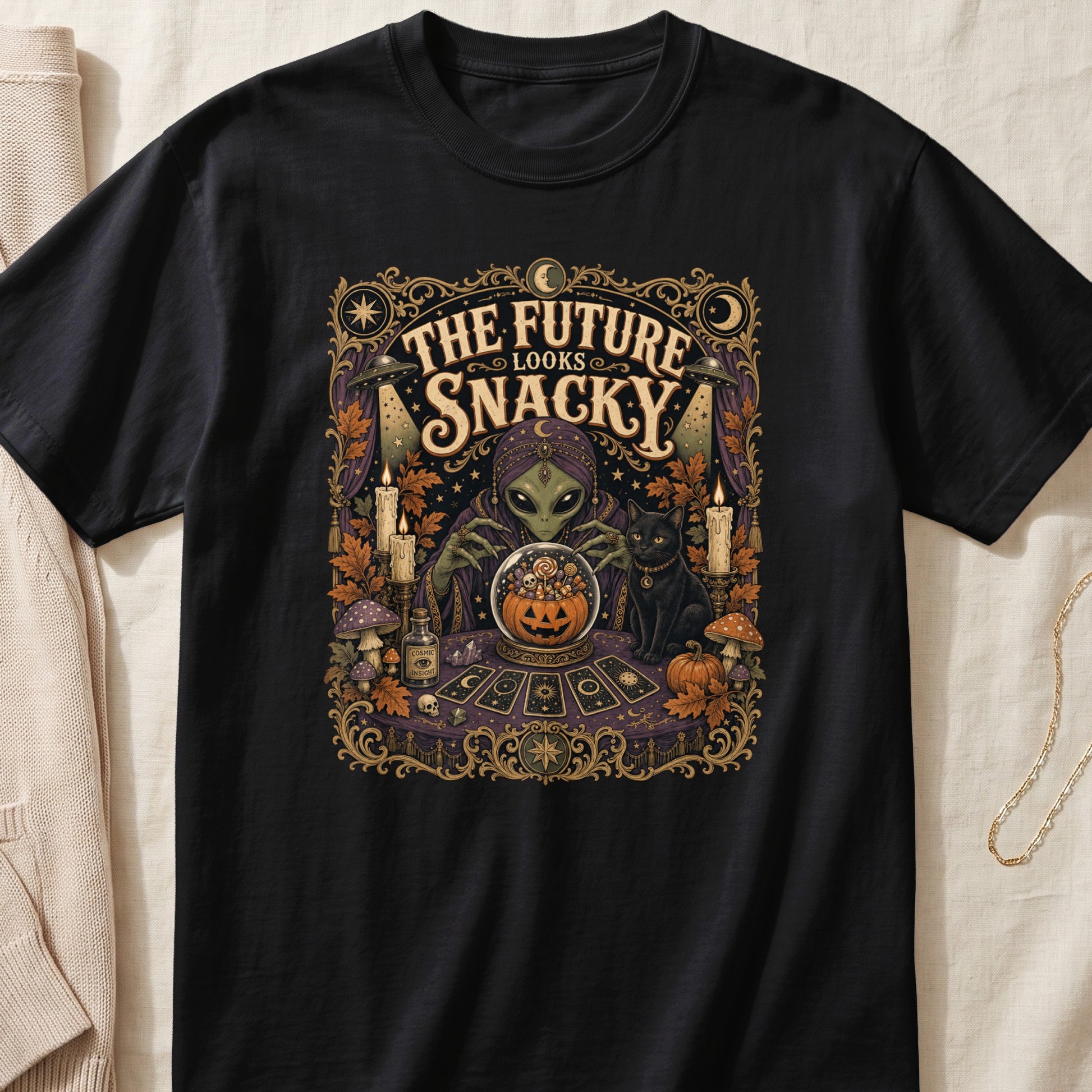 Alien fortune teller with black cat and crystal ball reads "The Future Looks Snacky".