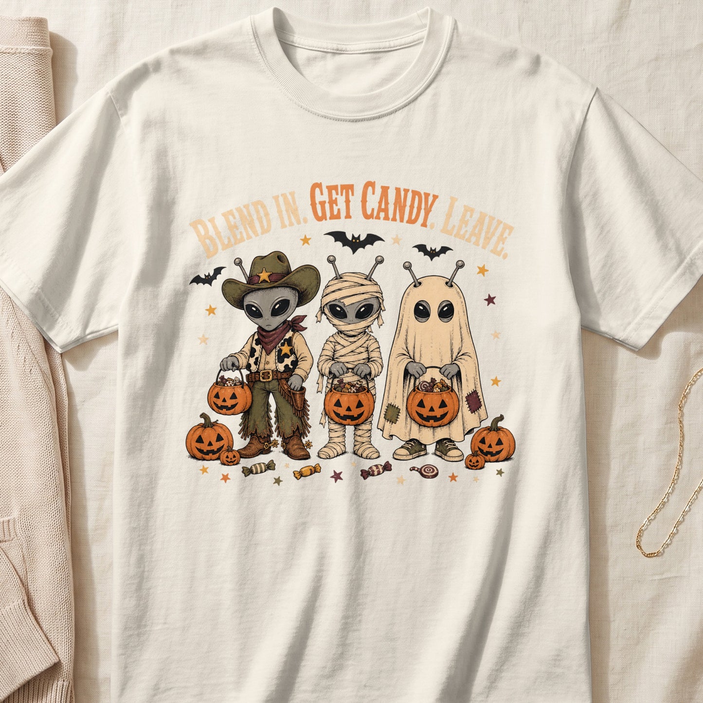 Three aliens dressed as a cowboy, mummy, and ghost hold candy buckets with text "BLEND IN. GET CANDY. LEAVE."