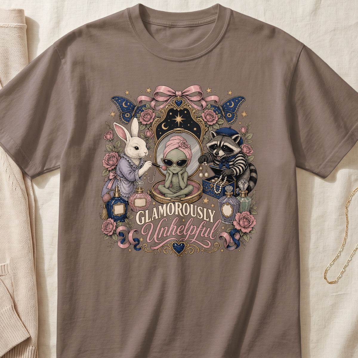 T-shirt with "Glamorously Unhelpful" text, alien, rabbit, and raccoon surrounded by perfume bottles and roses.