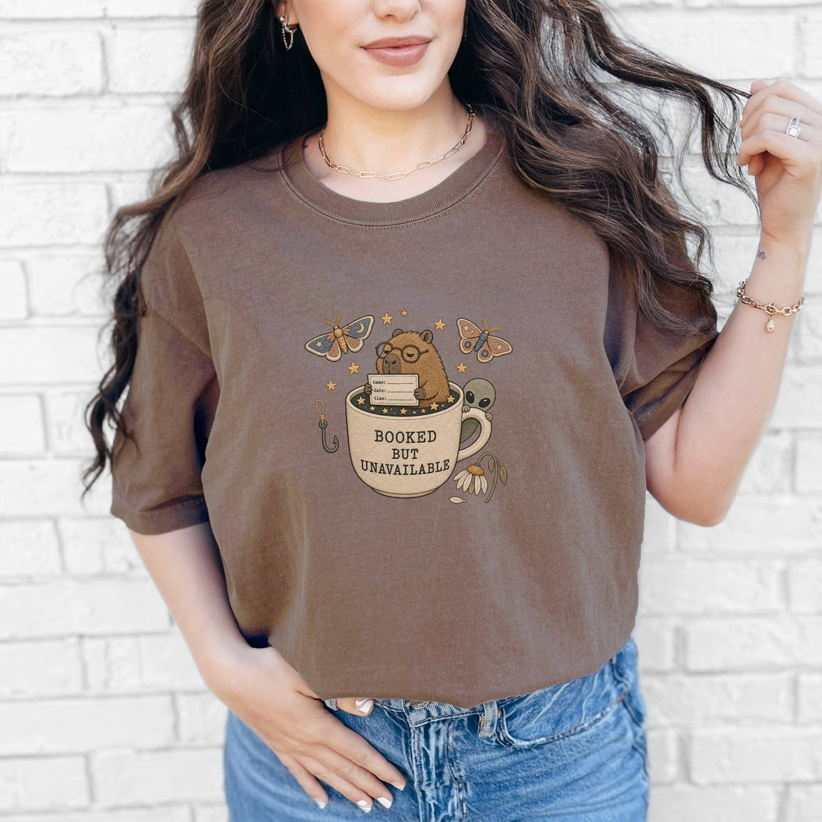 Brown t-shirt graphic of bear in a mug with text "BOOKED BUT UNAVAILABLE".