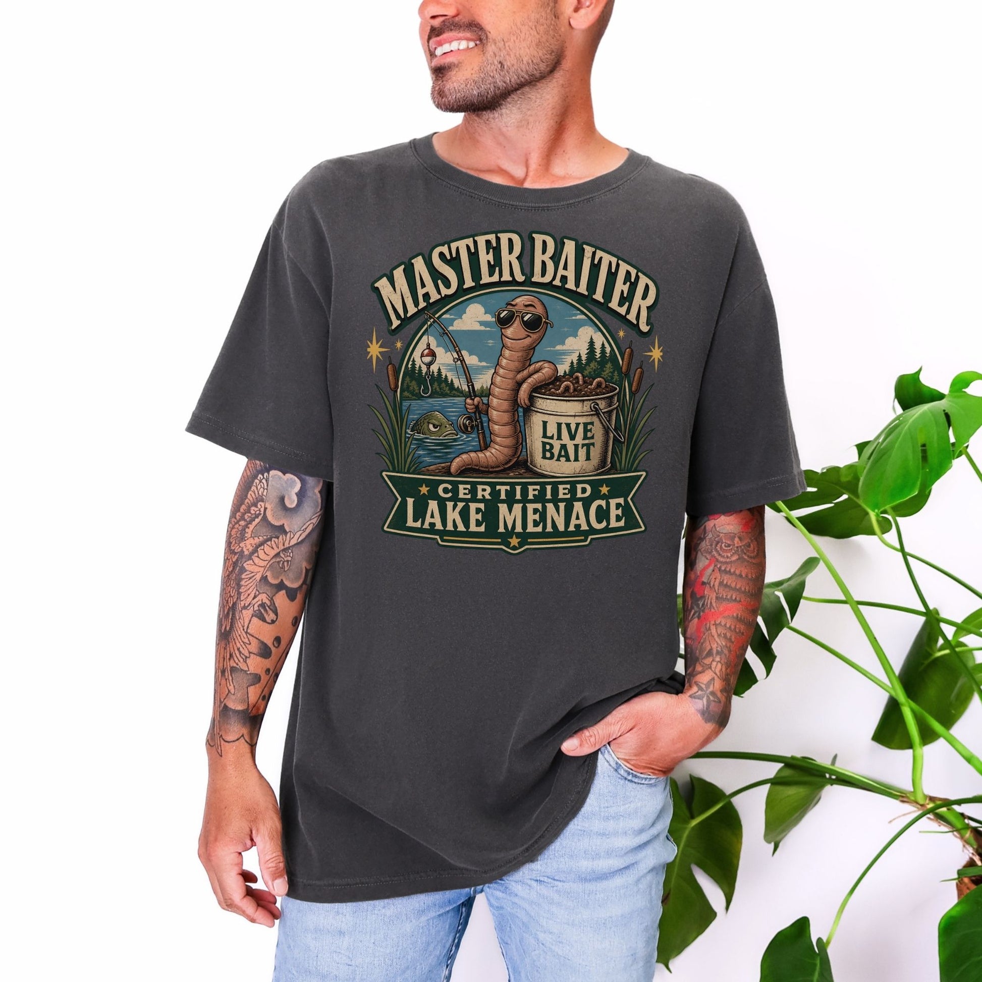 Graphic tee with a cartoon worm fishing, says "Master Baiter Certified Lake Menace".