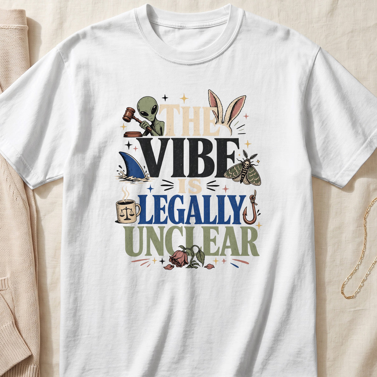 White t-shirt with text "THE VIBE IS LEGALLY UNCLEAR" and various graphics.