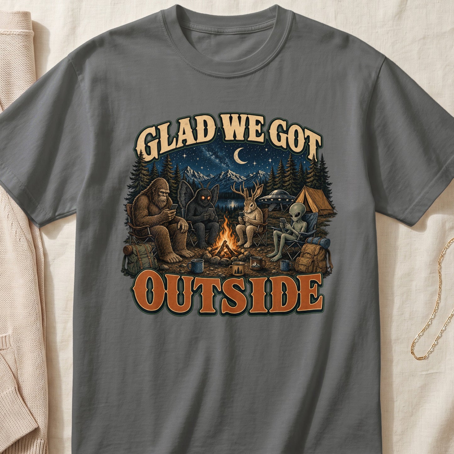 Bigfoot, mothman, deer, and alien camping under starry sky with text "GLAD WE GOT OUTSIDE."