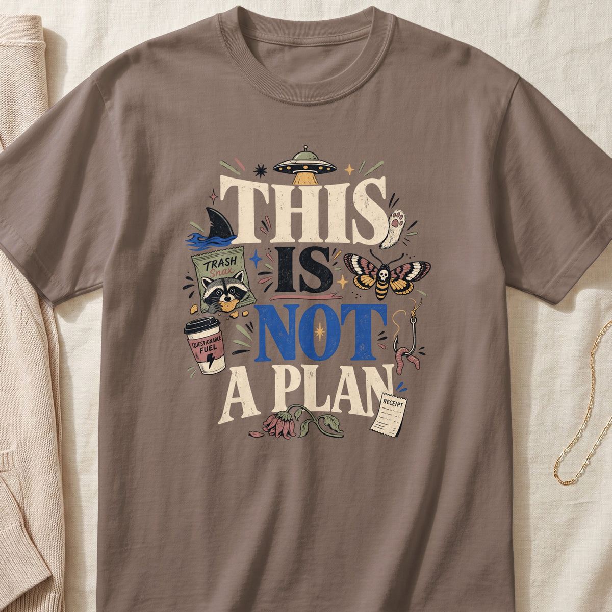 T-shirt with "This Is Not A Plan" text and various whimsical graphics.