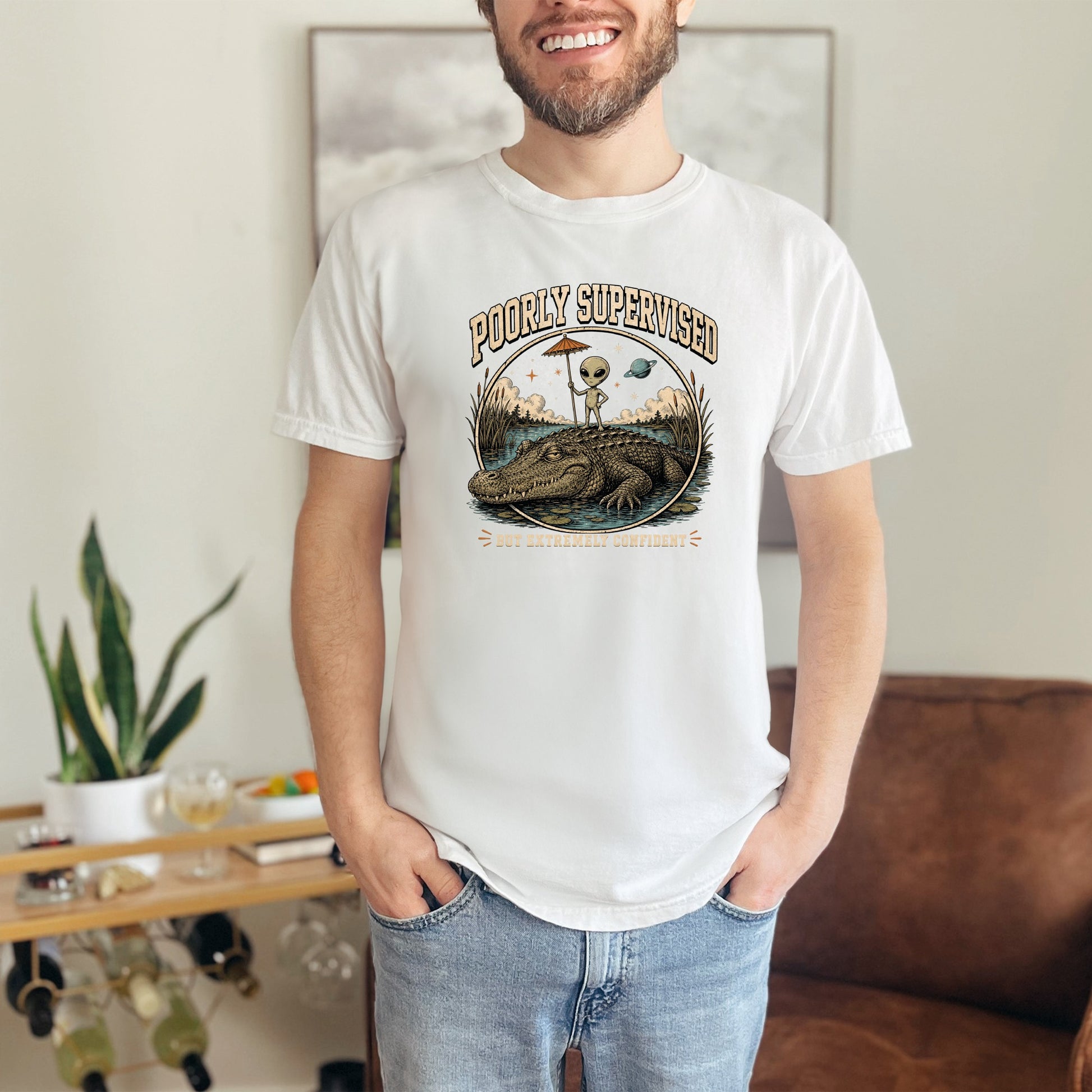 T-shirt graphic with alien on alligator, reading "Poorly Supervised But Extremely Confident."