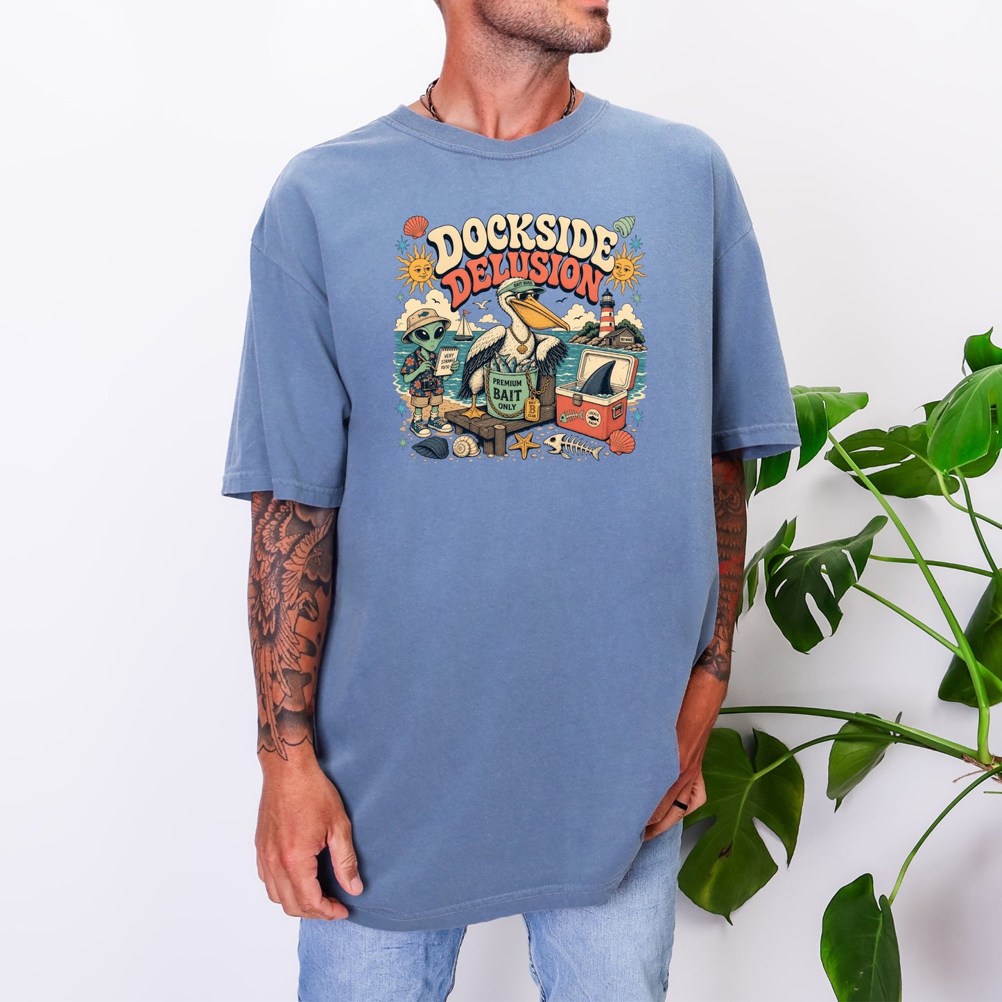 T-shirt with "Dockside Delusion" text and cartoon characters including an alien and pelican.