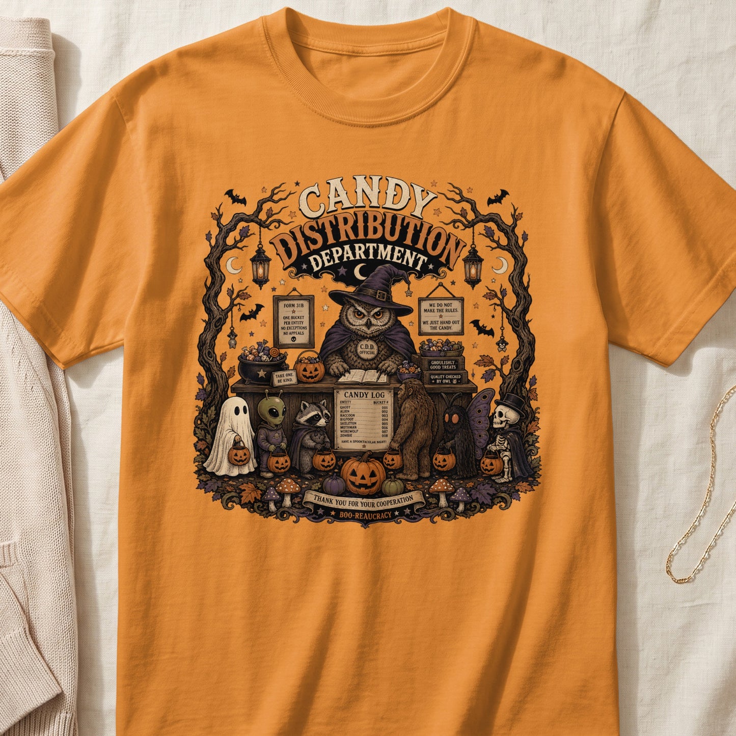 Halloween t-shirt graphic with owl, ghost, alien, raccoon, and skeletons at candy distribution.