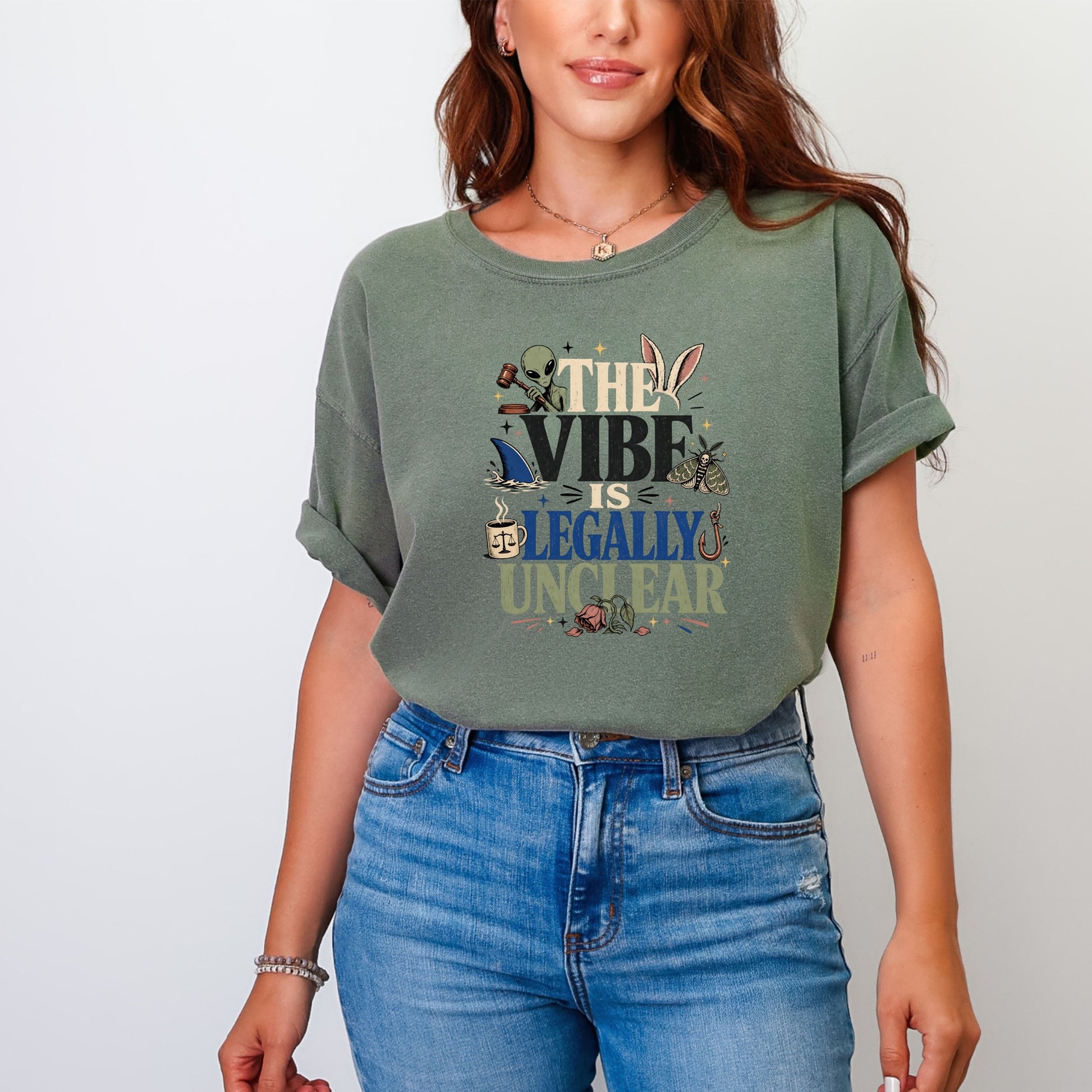 Green t-shirt with graphic text "THE VIBE IS LEGALLY UNCLEAR" and various illustrations.
