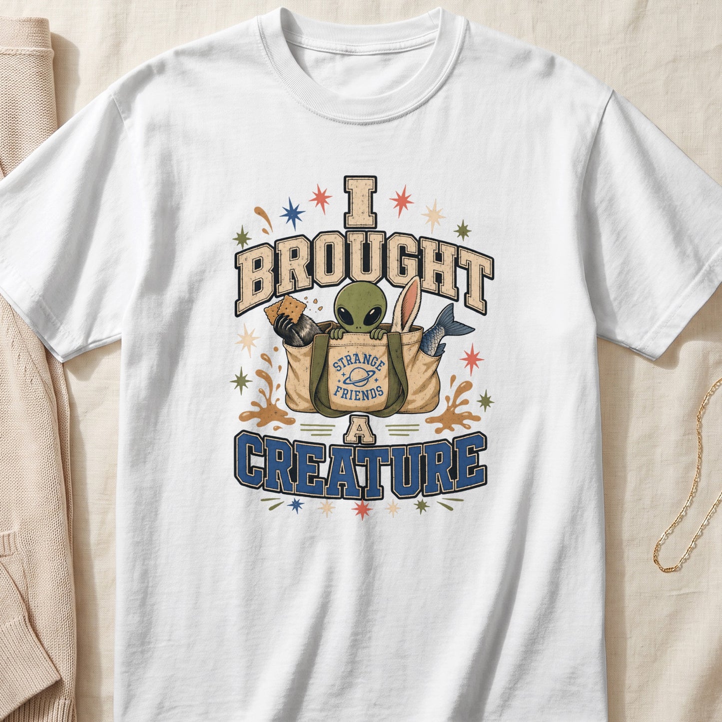 White t-shirt with "I BROUGHT STRANGE FRIENDS A CREATURE" text and an alien.