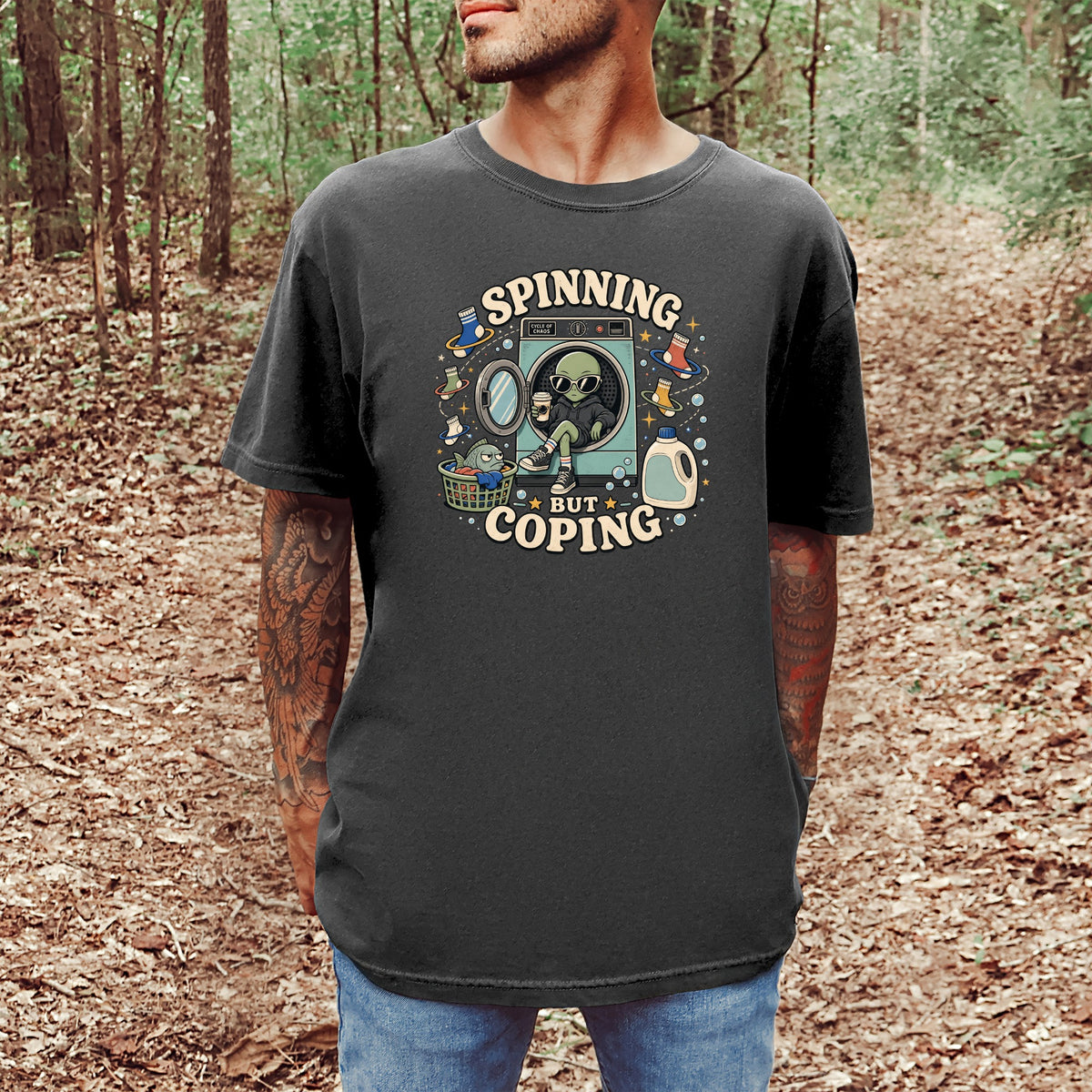 Black t-shirt with graphic of alien in dryer, "Spinning But Coping" text.