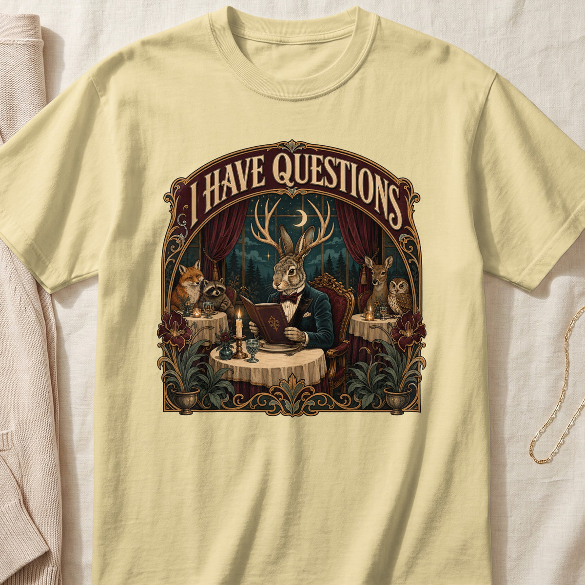 Yellow t-shirt with a graphic of anthropomorphic animals at a table with the text "I HAVE QUESTIONS".