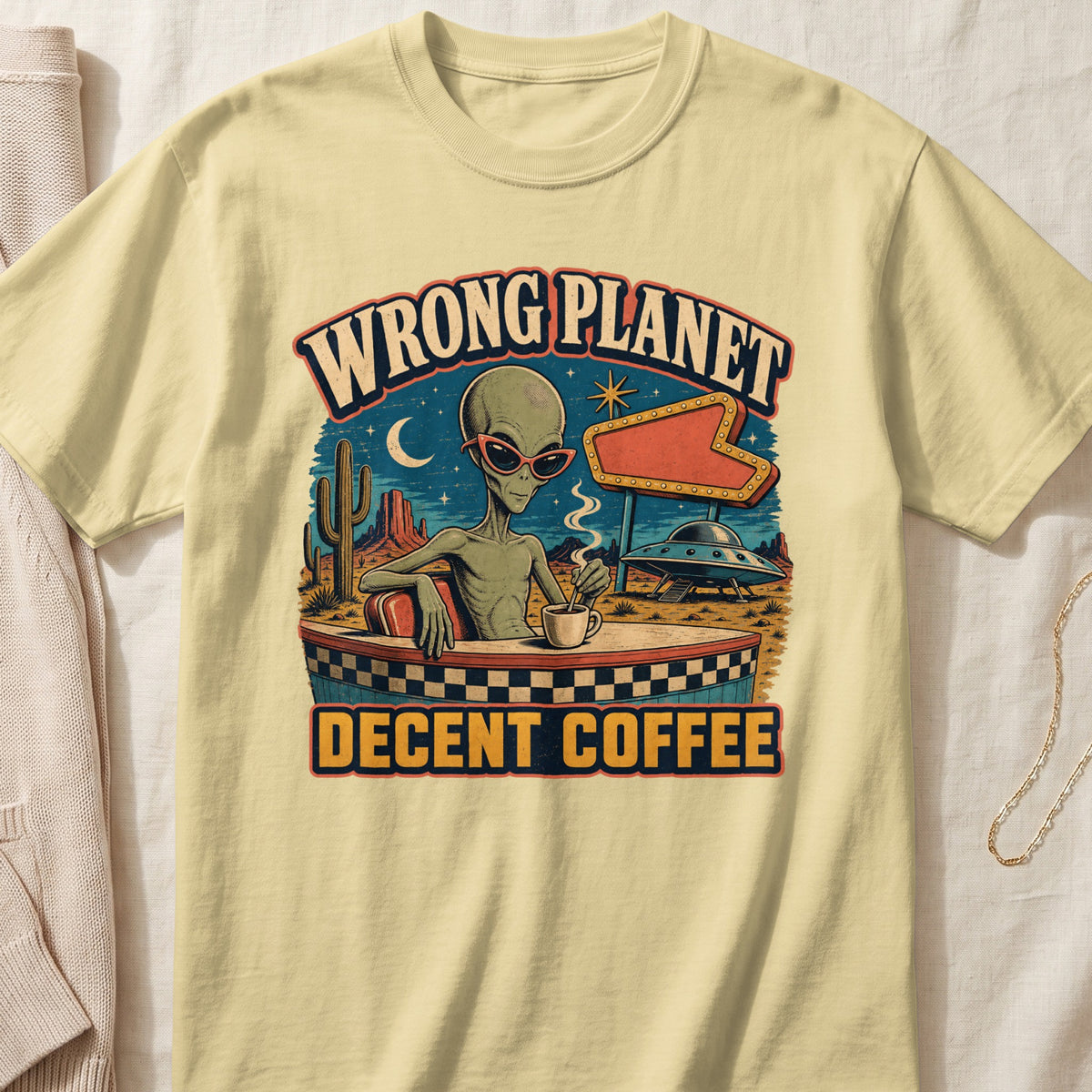 Alien in sunglasses at a diner with "Wrong Planet Decent Coffee" text.