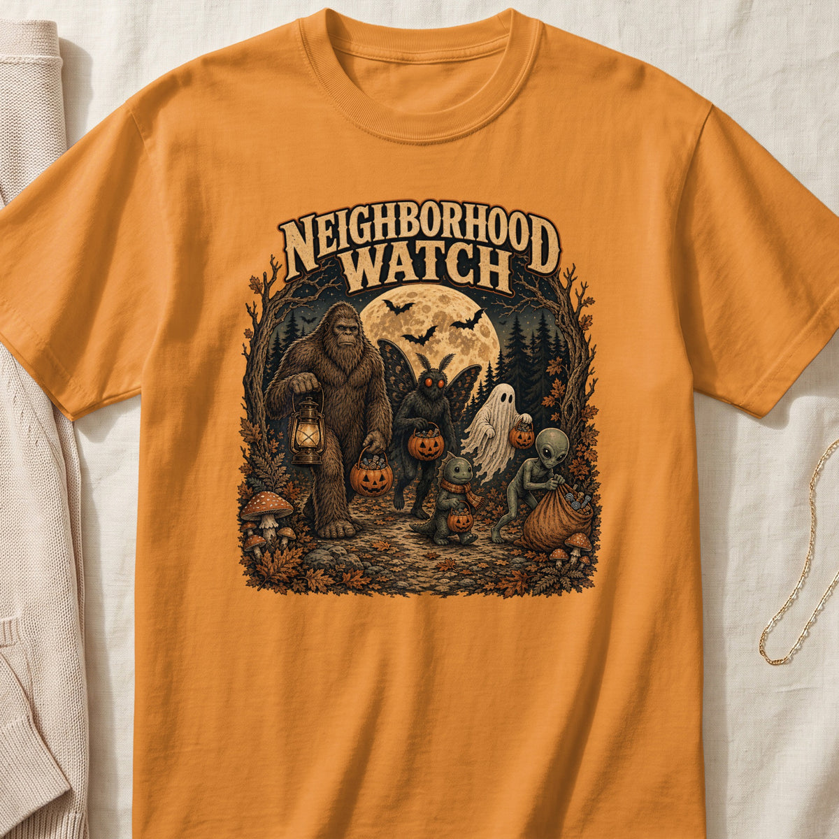 Orange t-shirt with "NEIGHBORHOOD WATCH" text and Halloween creatures trick-or-treating.