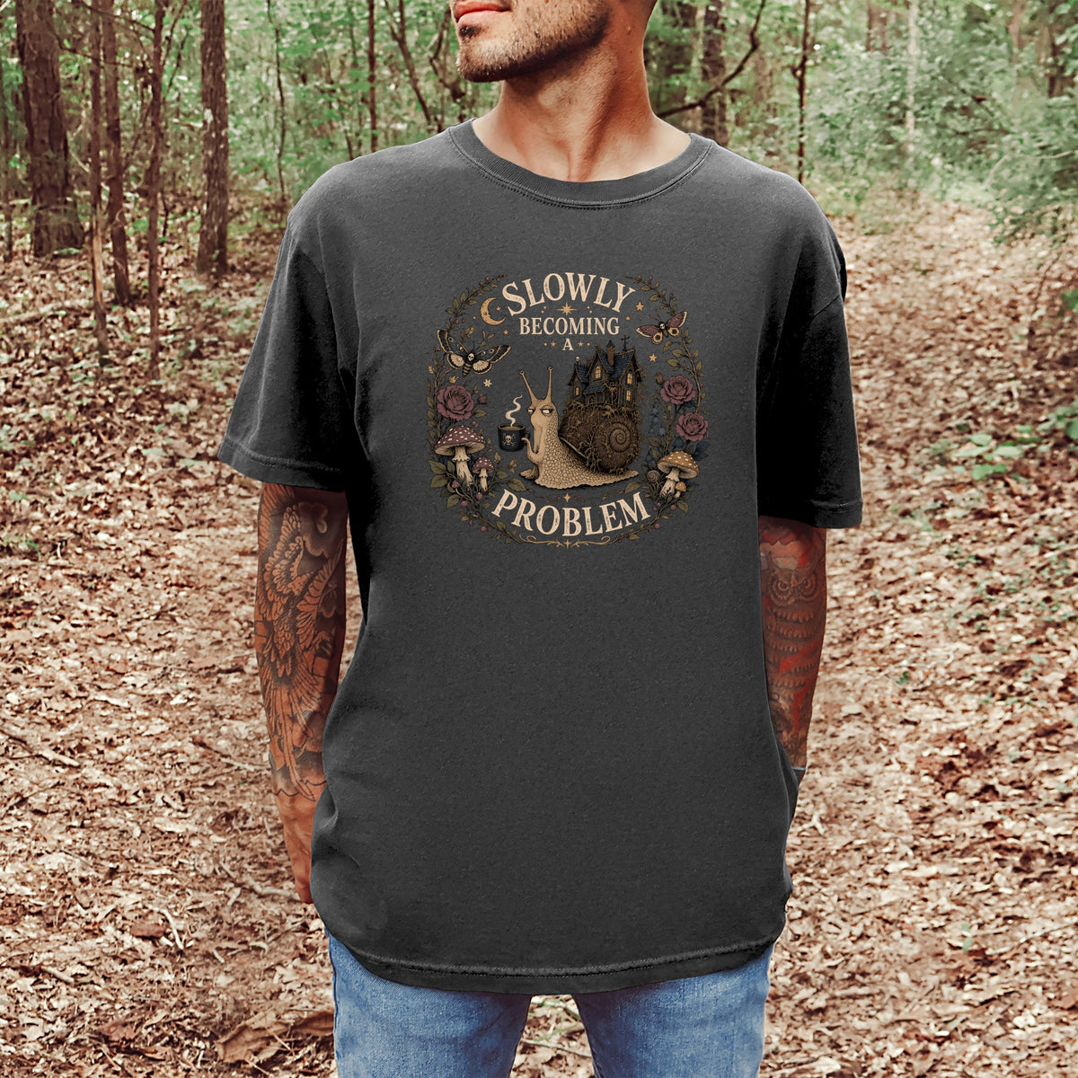 Dark t-shirt with a graphic of a snail holding coffee, a castle, and text "SLOWLY BECOMING A PROBLEM".