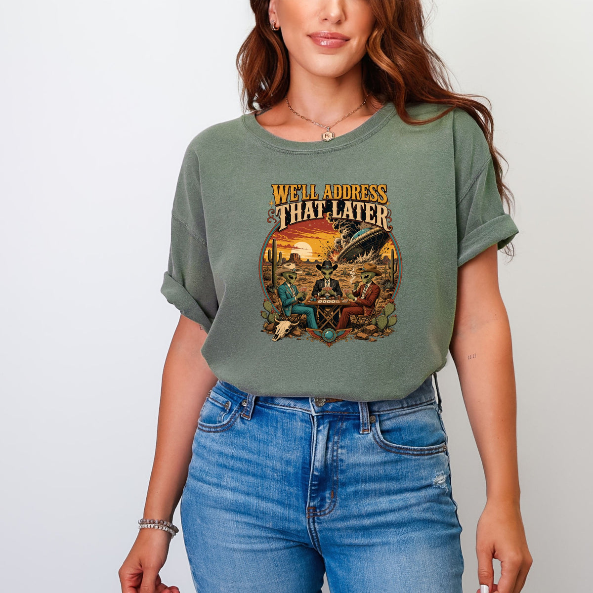 T-shirt graphic shows aliens playing poker in a desert with a UFO and sunset. Text says "We'll Address That Later".