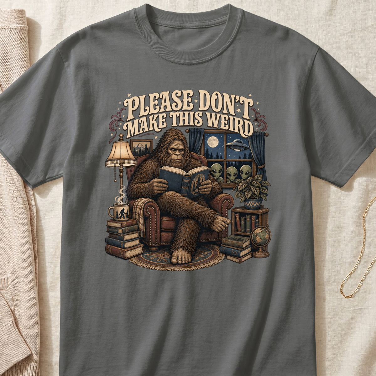 Bigfoot reading a book with aliens, a UFO, and the text "PLEASE DON'T MAKE THIS WEIRD".