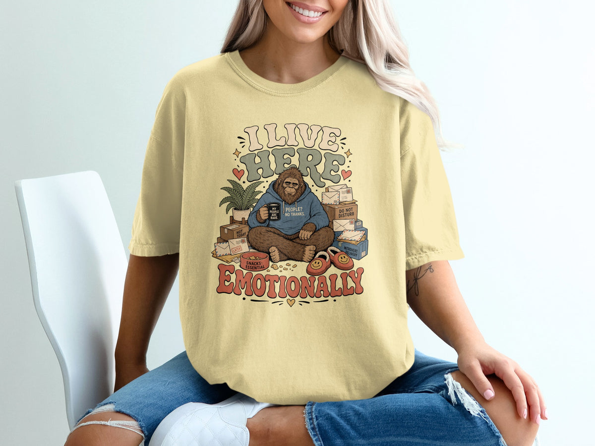 Bigfoot graphic on yellow t-shirt with text "I LIVE HERE EMOTIONALLY".