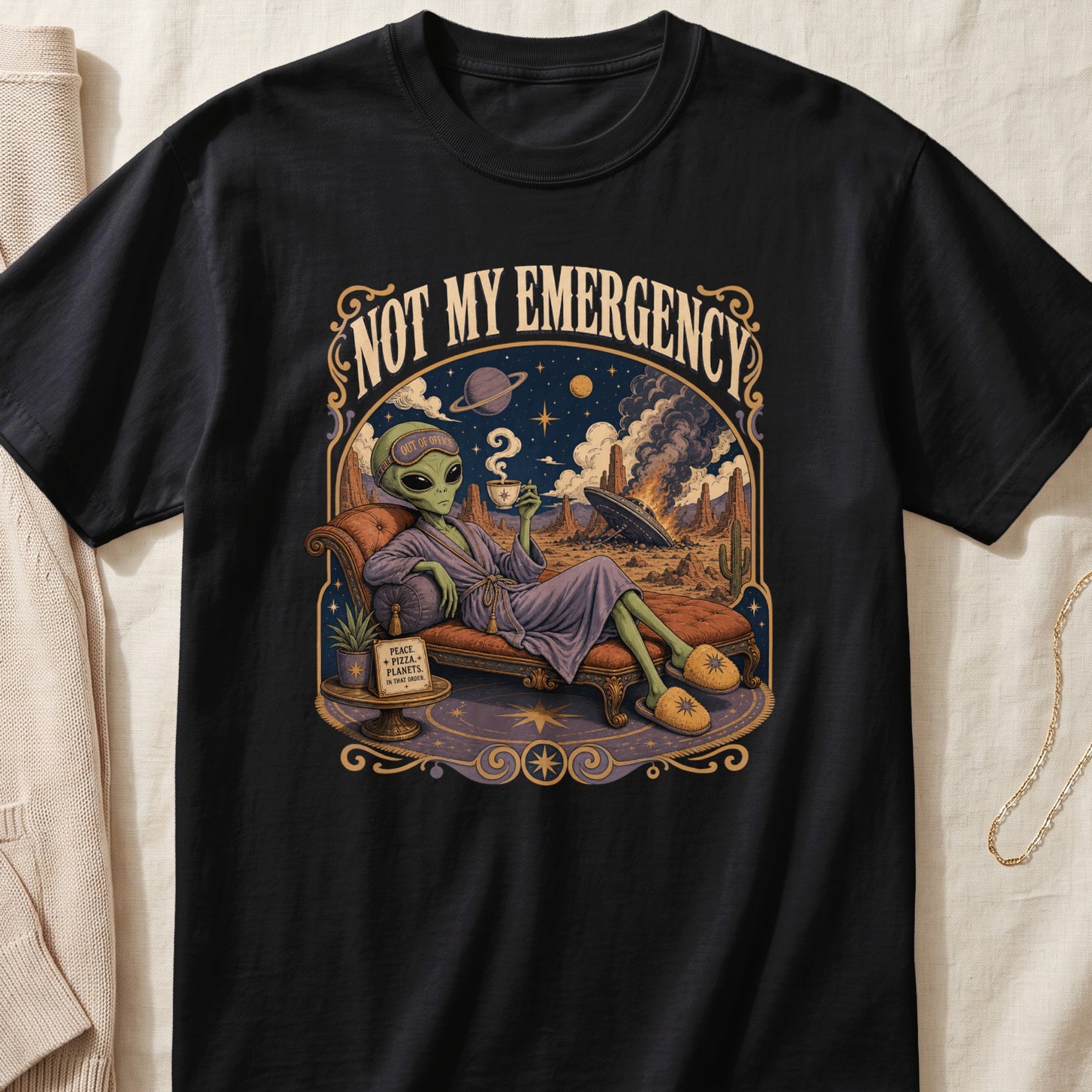 Black t-shirt featuring an alien relaxing with coffee under "NOT MY EMERGENCY" text.