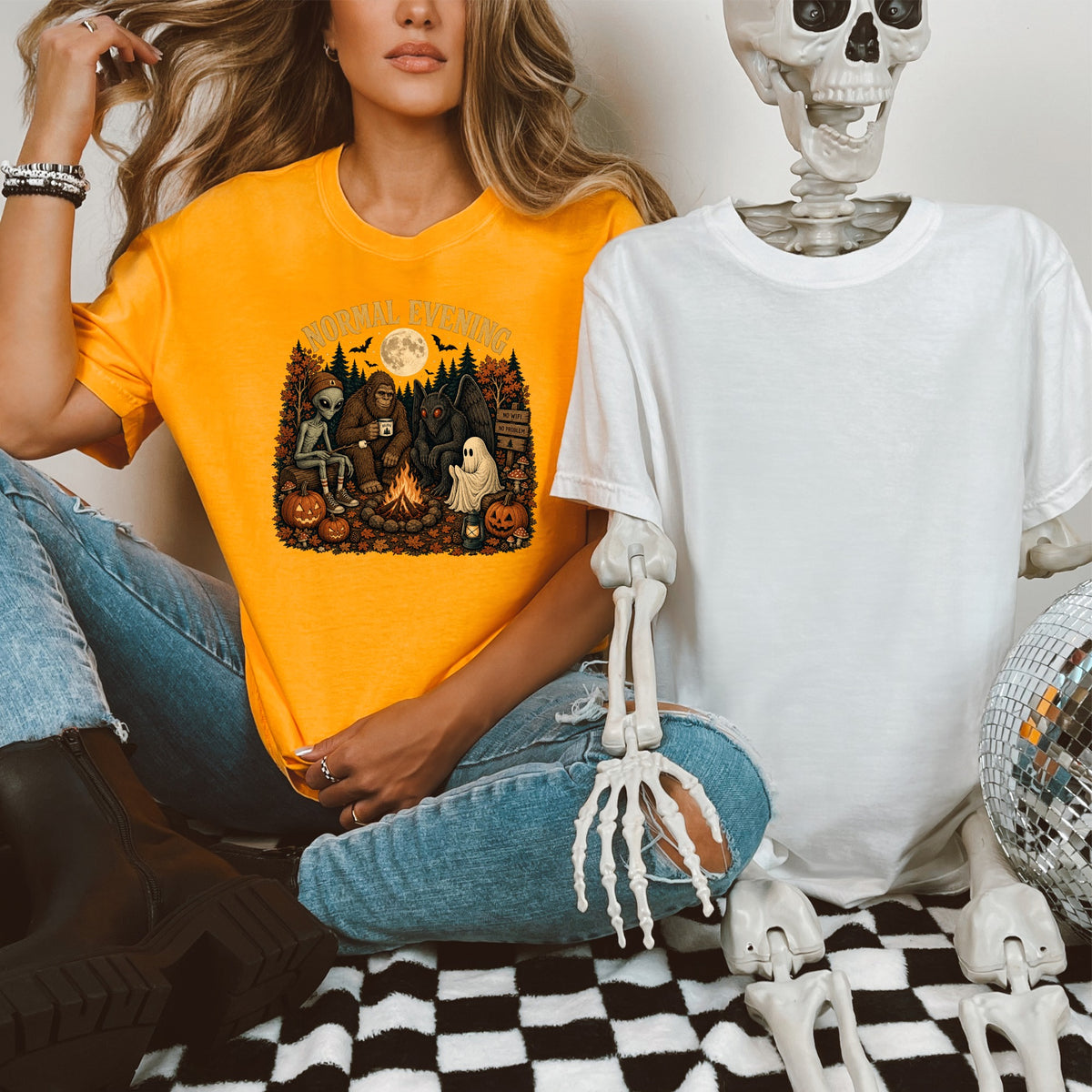 Orange t-shirt graphic with Bigfoot, alien, mothman, and ghost around a campfire.