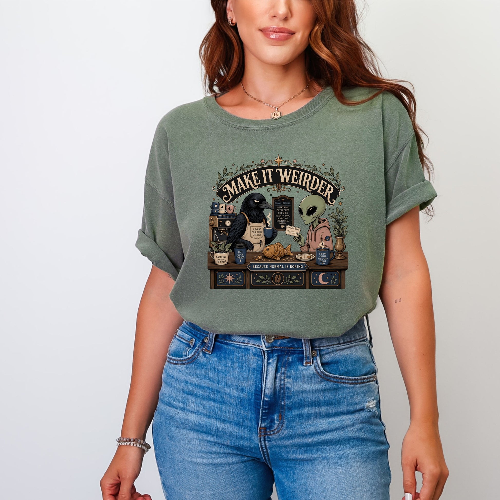 Green t-shirt graphic featuring a crow and alien at a coffee counter with text.