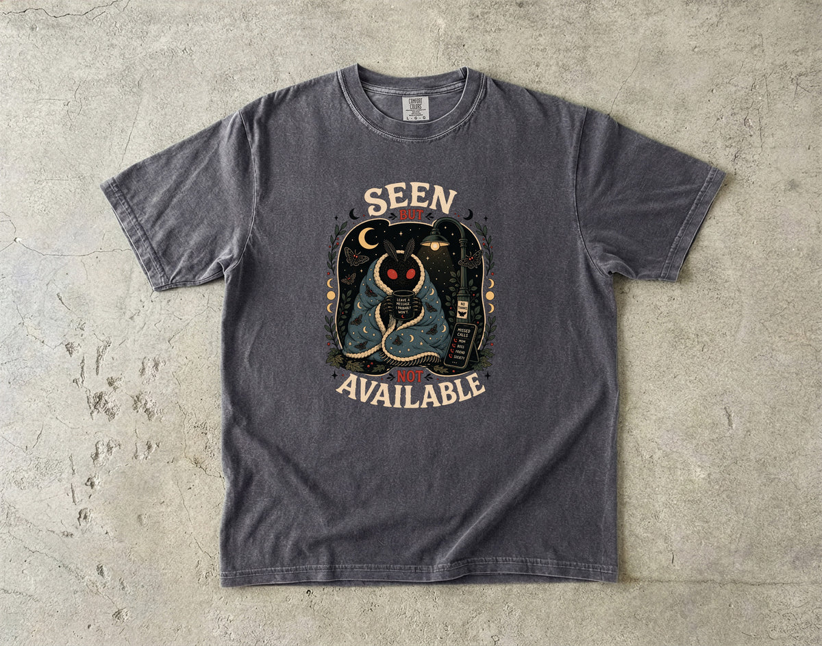 Dark gray t-shirt graphic with text "Seen But Not Available" and a moth character.
