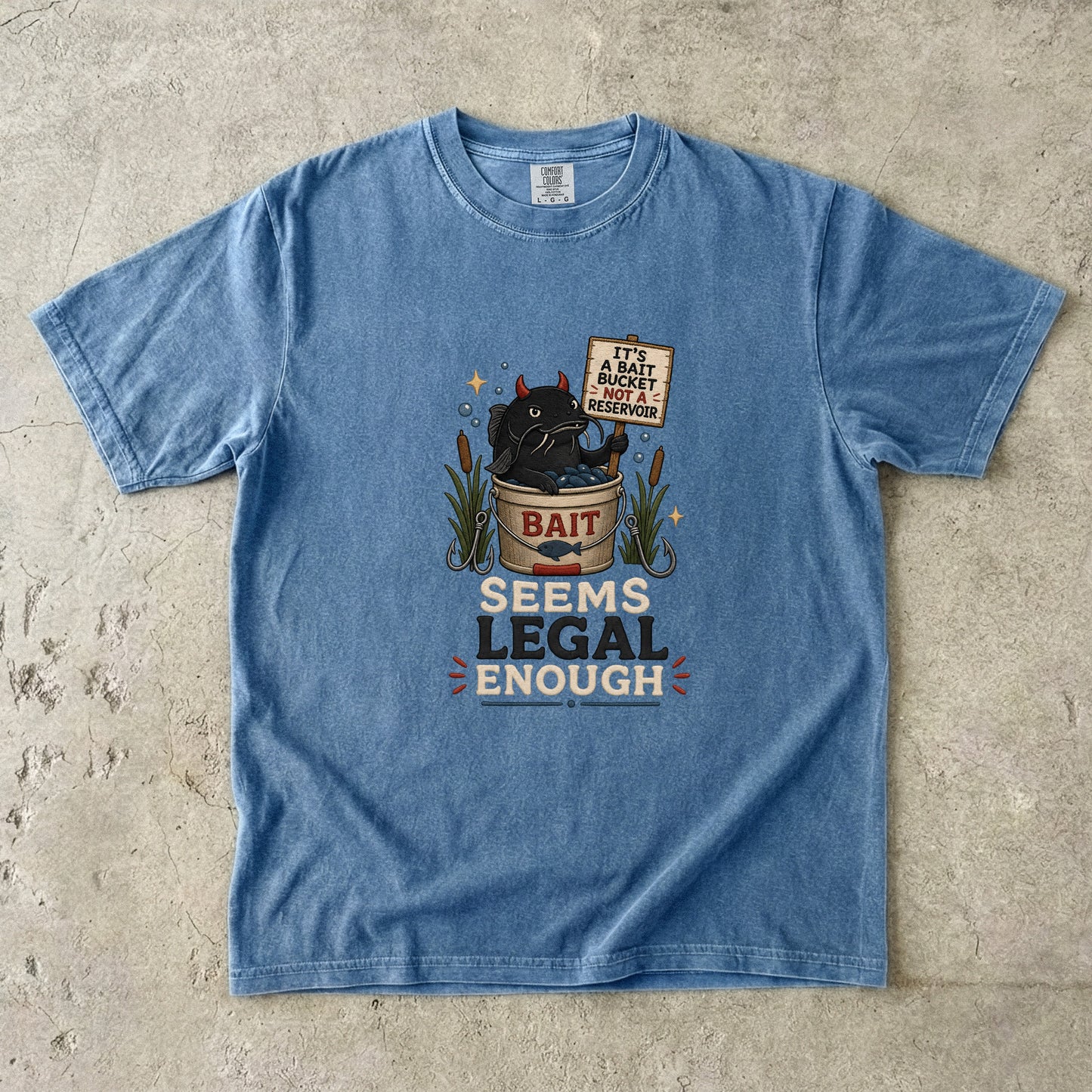 Blue t-shirt with graphic of devilish fish in bait bucket and text "SEEMS LEGAL ENOUGH".