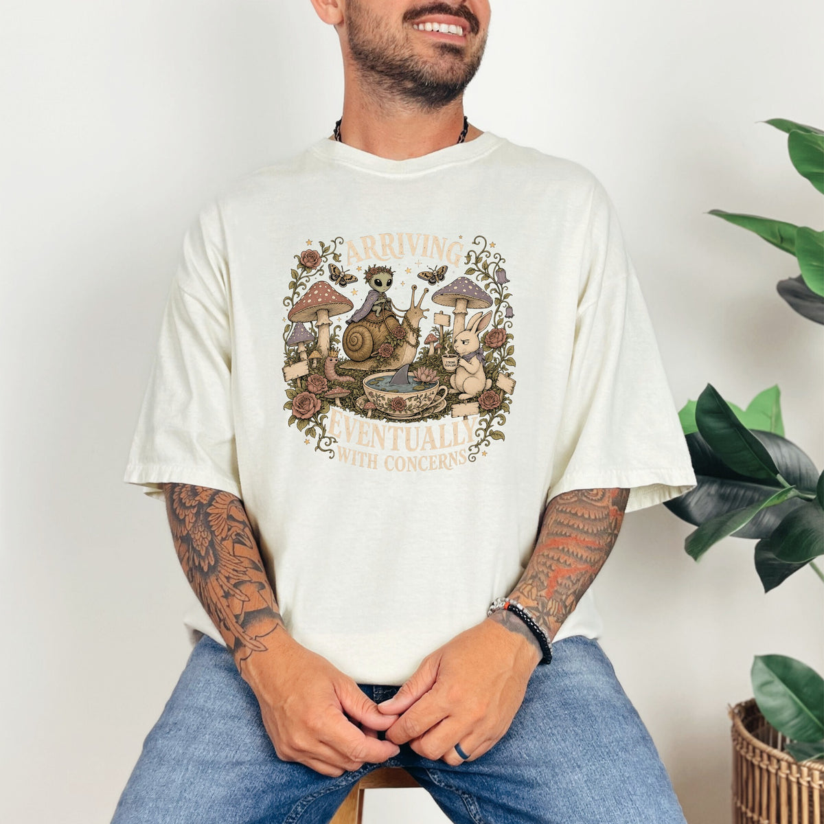 T-shirt graphic with alien, snail, rabbit, mushrooms, and text "Arriving Eventually With Concerns".