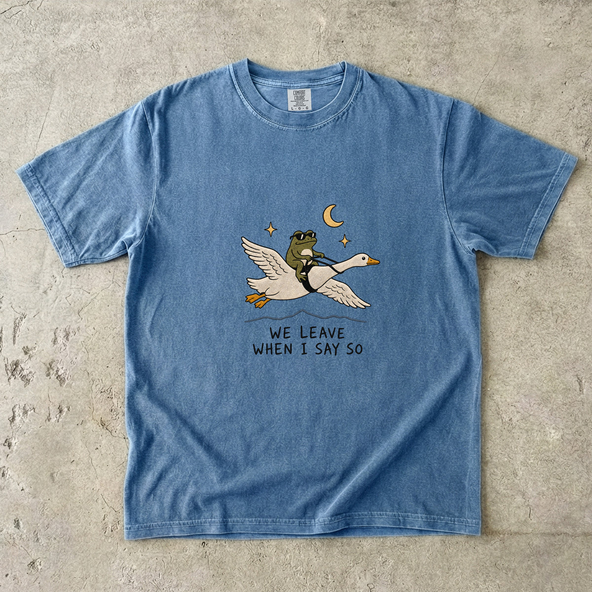 Blue t-shirt with graphic of frog riding goose, text "WE LEAVE WHEN I SAY SO".