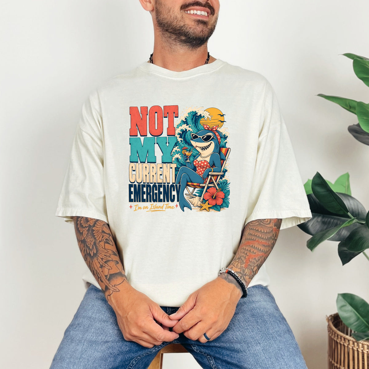 Shirt with "NOT MY CURRENT EMERGENCY" and a shark in a beach chair.